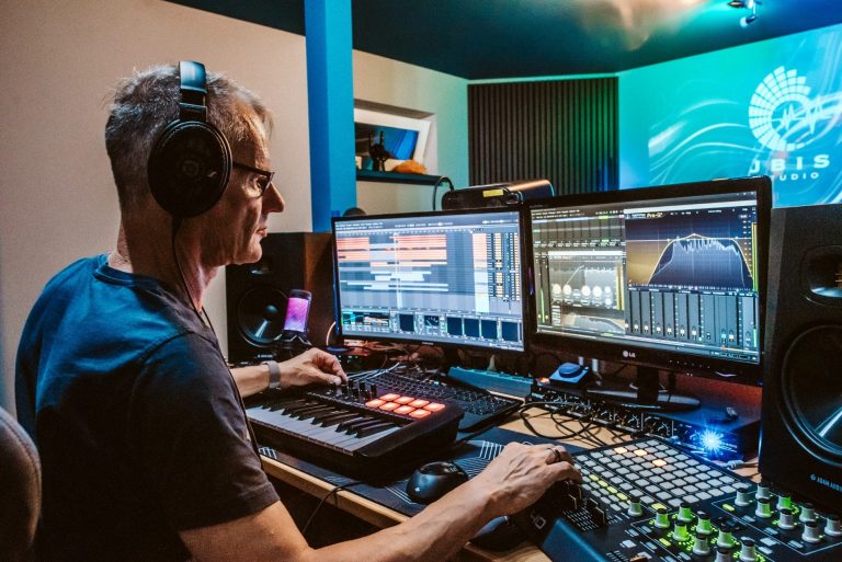 Mann arbeitet an Musiksoftware mit zwei Monitoren und MIDI-Controller.